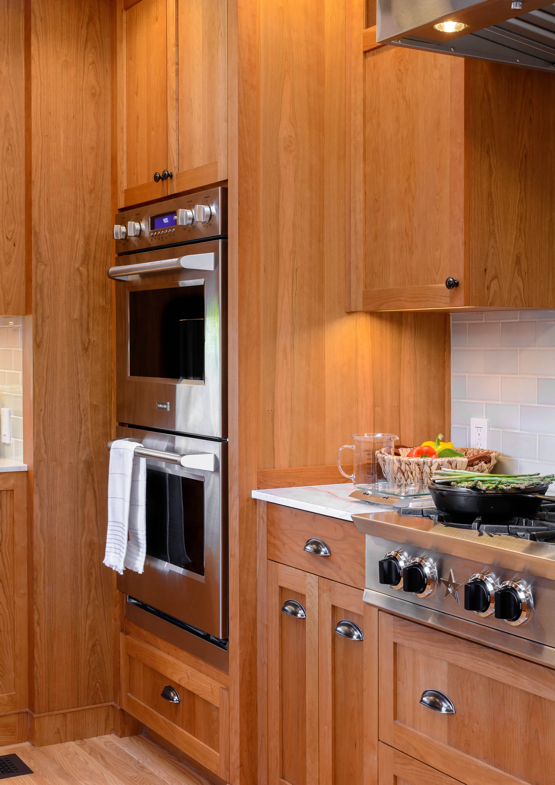 Tudor modern luxury or when kitchen appliances provide a fine touch: the double wall oven, range top and wall-mounted hood suit the clean lines and warmth of the cherry cabinets and accent hardware