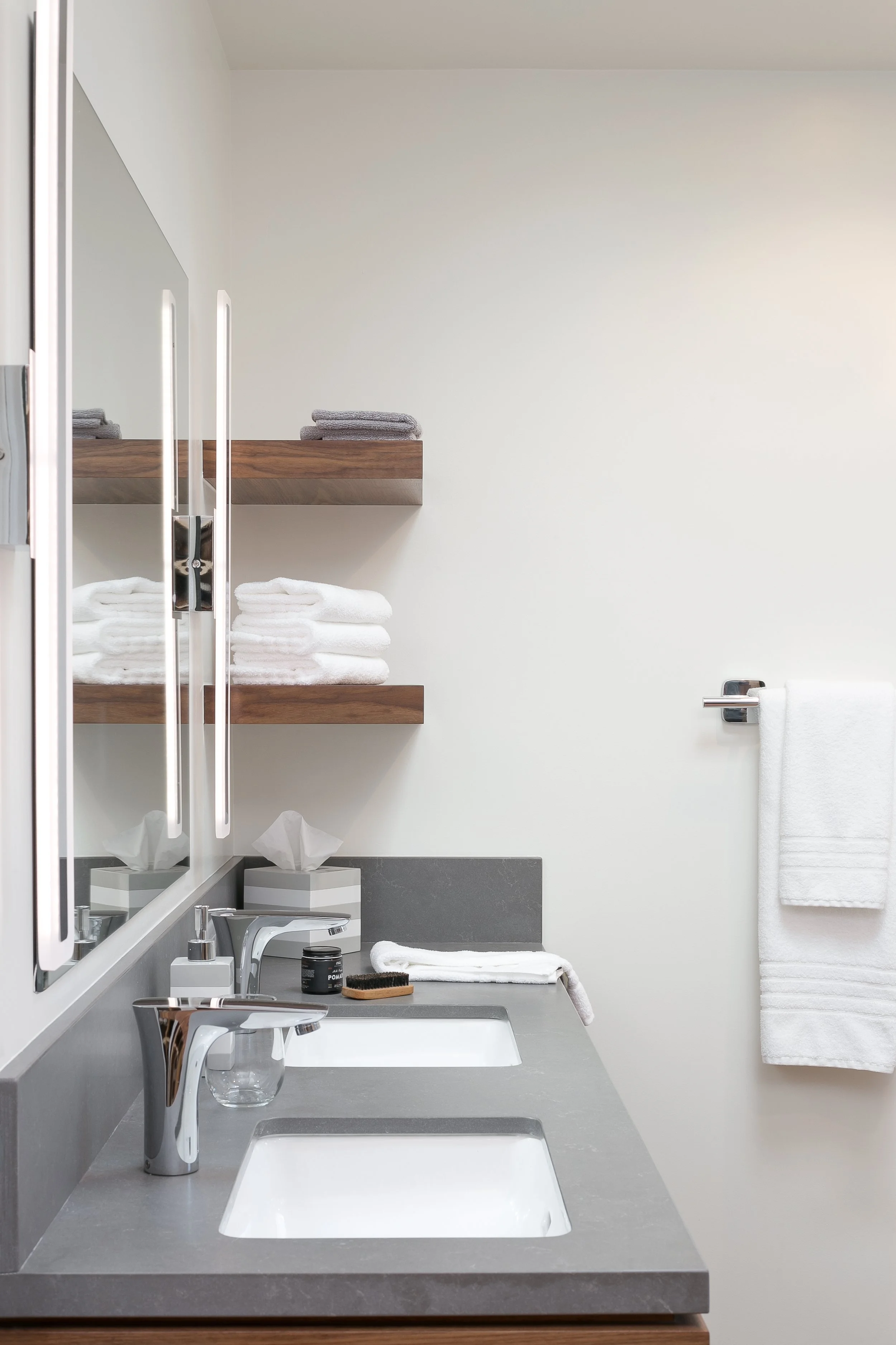 The walnut floating shelves provide a nice balance above the grey vanity top