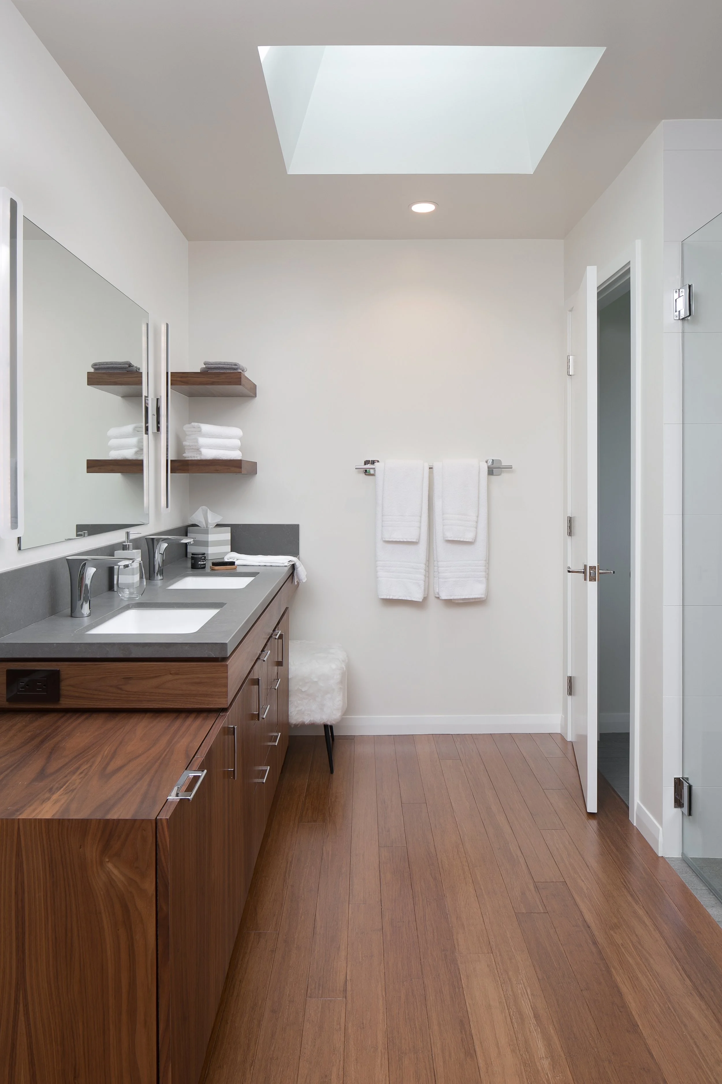 The skylight and white walls illuminate this contemporary ranch master bathroom finished with bamboo flooring and custom walnut cabinetry