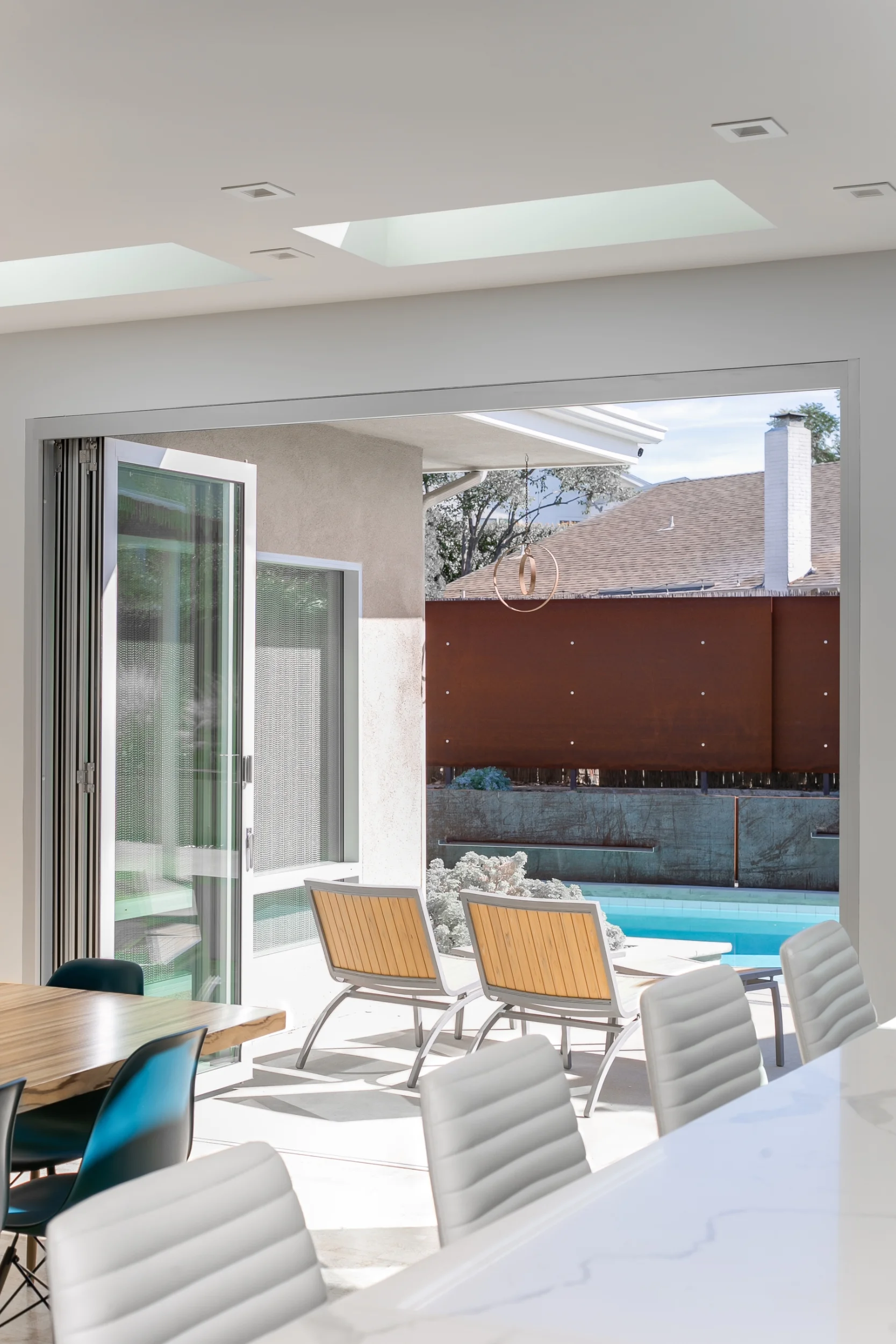 Indoor-outdoor living: the folding glass doors open the kitchen and dining room onto the patio and the pool, accentuated with a wall of Corten steel