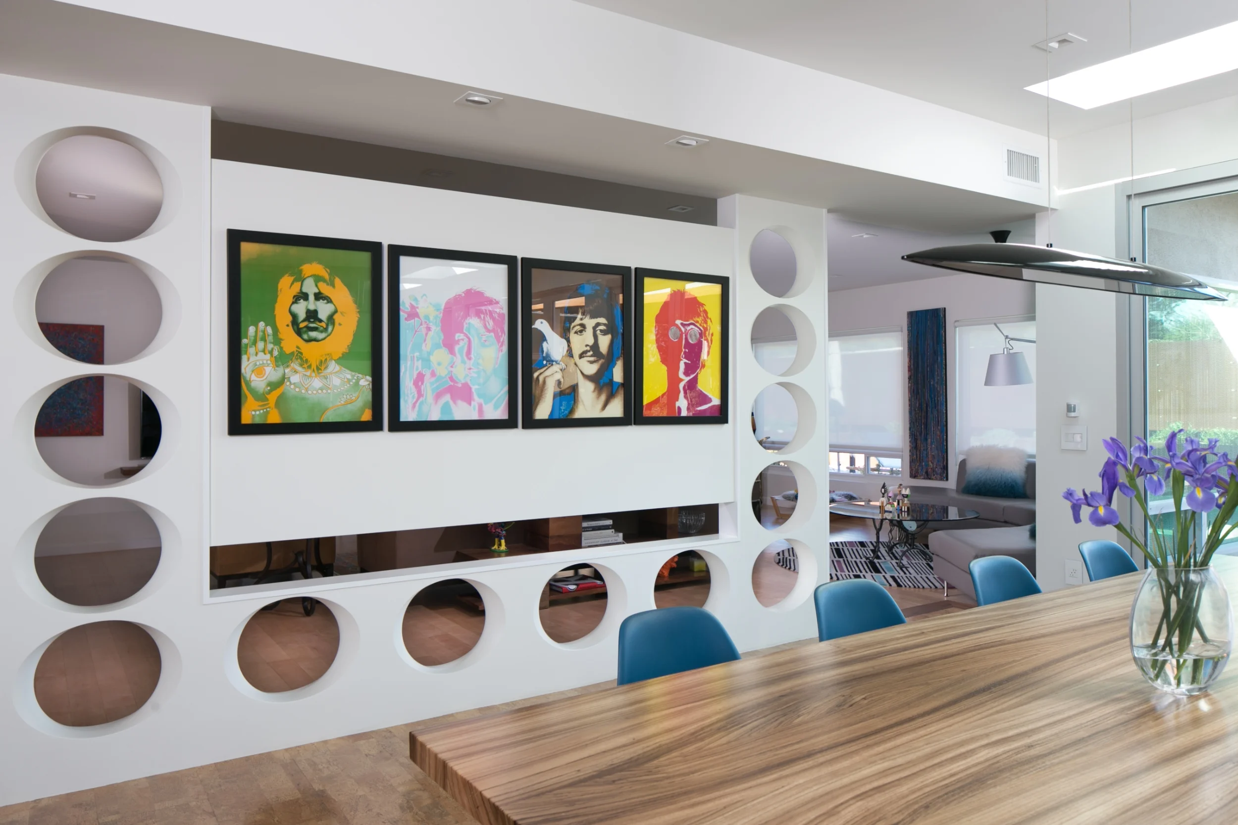 This mid-century modern dining room art wall with prints of the Beatles allows for privacy while keeping an open feel