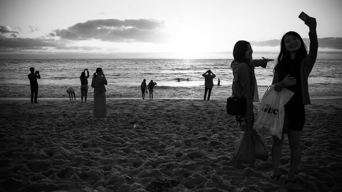  People gather at the waters edge for selfies at sunrise. 