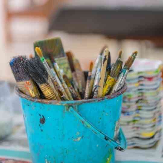 Mixed media paint brushes inside blue pail