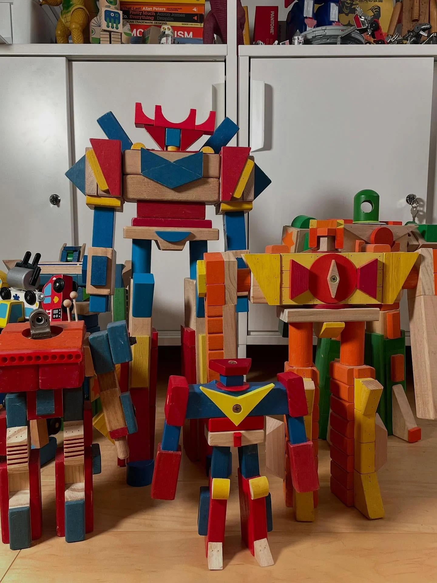 Some of my bots hanging out on the floor near my work desk. Fun to see them in their different sizes and colors, but all with the same dna - made from wood blocks and discarded children&rsquo;s toys.