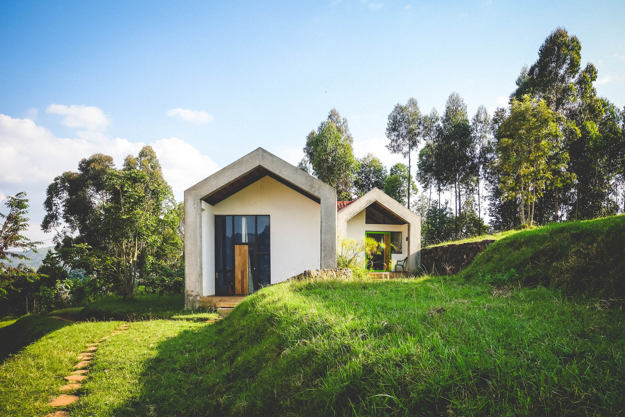 A reinforced concrete frame further supports the CSEBs’ seismic strength, plaster and white paint polish the walls, and a second layer of the volcanic rock from the local Virunga Mountains highlights the high- quality local craftsmanship.