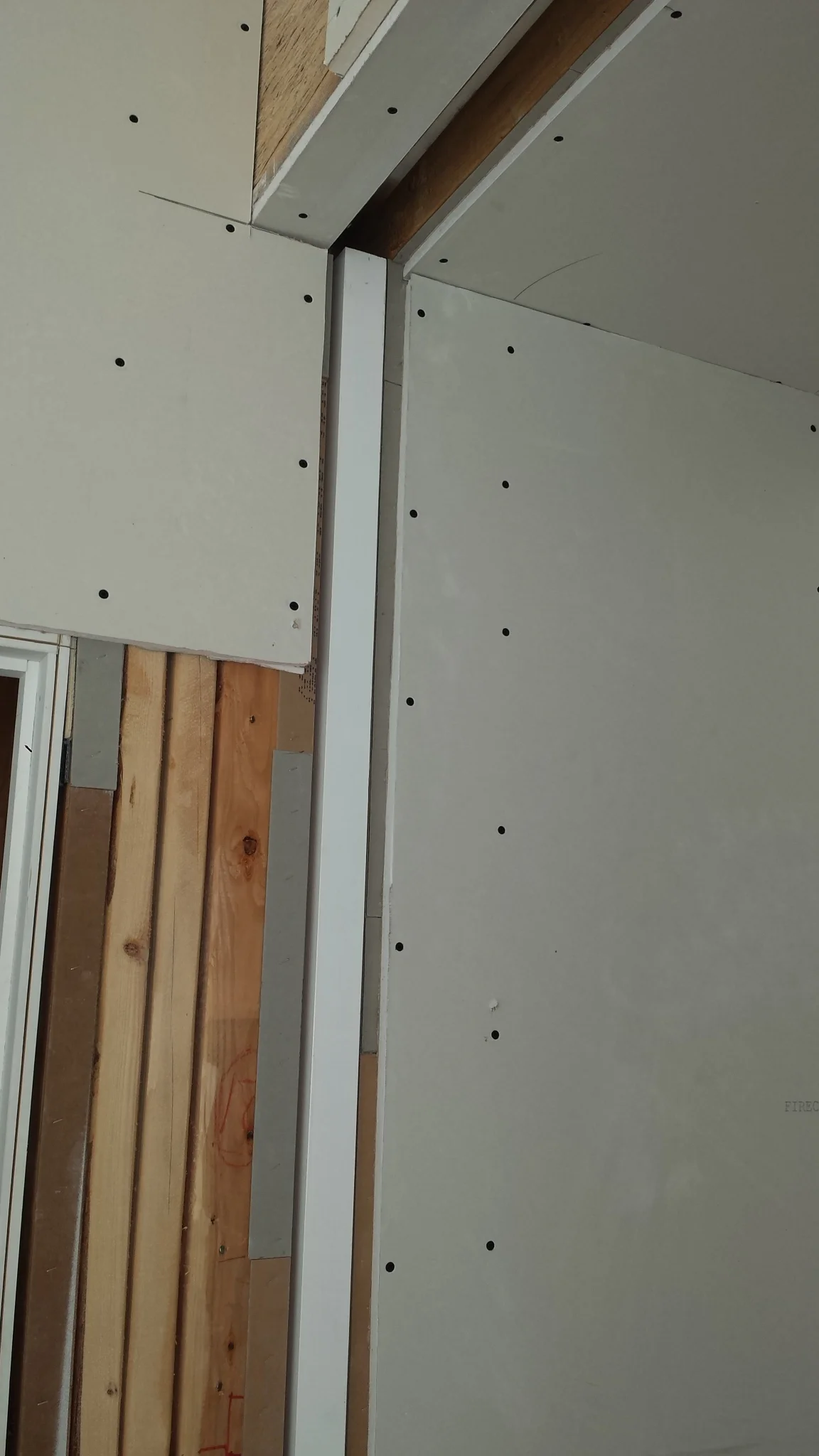 The areas around the opening are shimmed with strips of cardboard to get the drywall flush with the edge of the door.