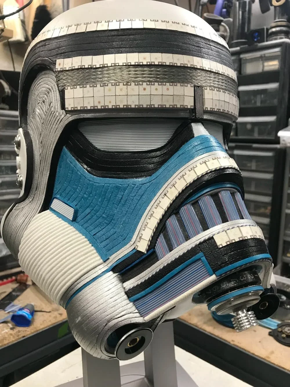 Upcycled McQuarrie Stormtrooper helmet sculpture by Gabriel Dishaw, blue and white banding with circular eye lenses and mechanical details, displayed on metal stand