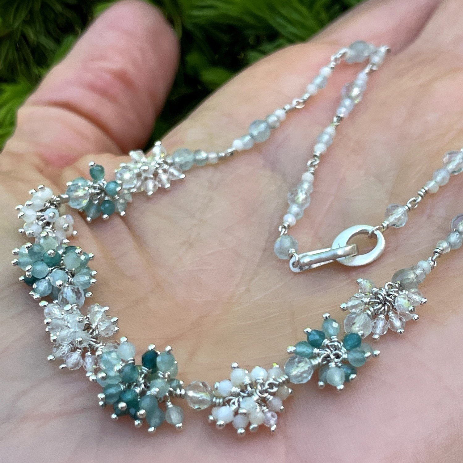 Silver necklace with clusters of deep teal to light blue grandiderite, aquamarine, opal and clear quartz gemstone beads.