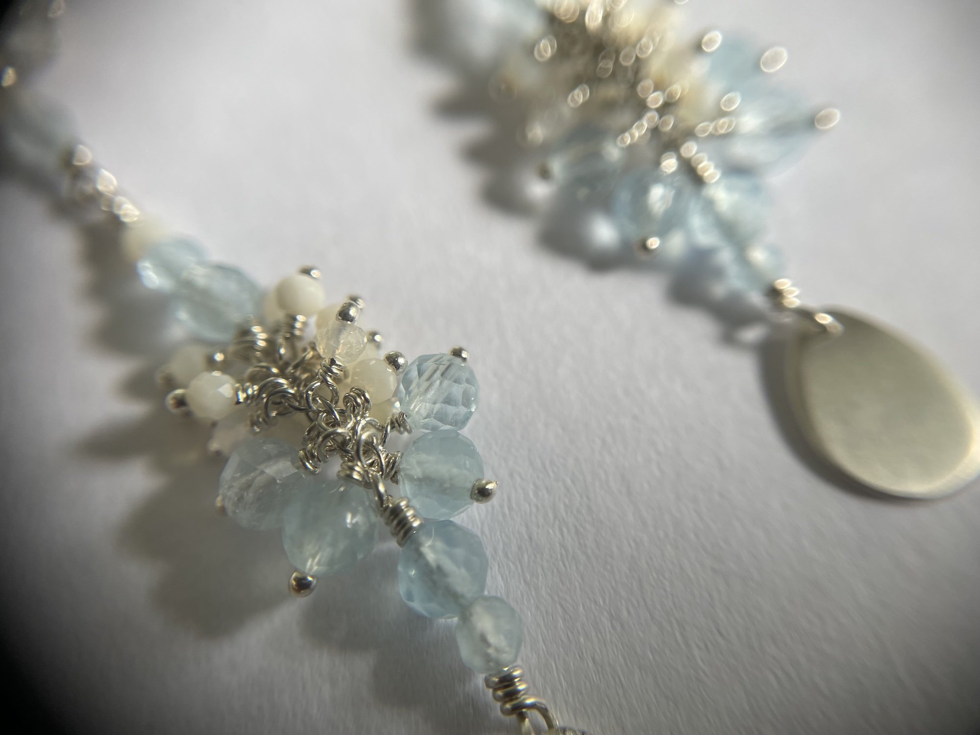 Long sterling silver earrings with clusters of light blue aquamarine, off white opals and clear quartz gemstone beads.