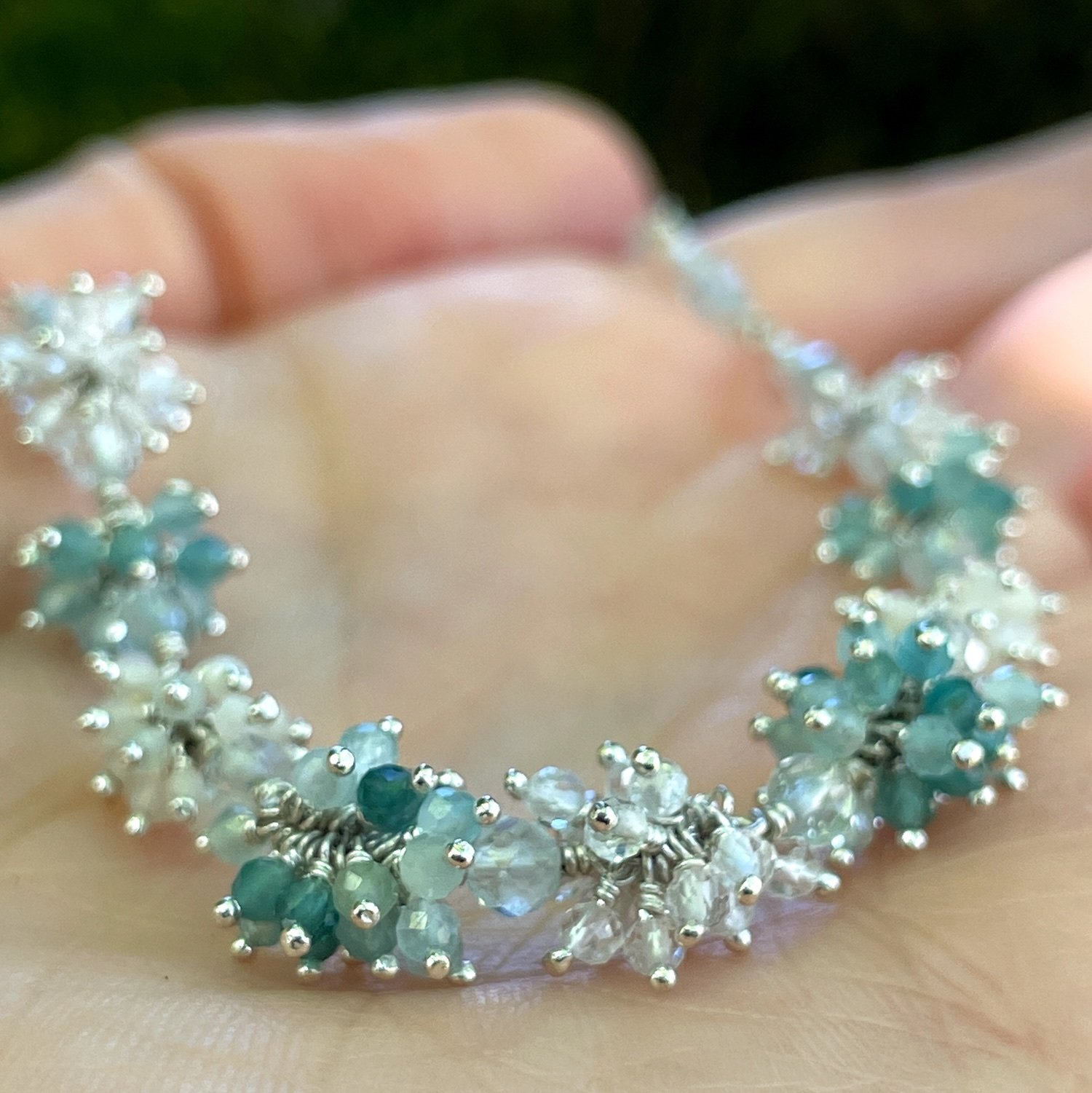 Silver necklace with clusters of deep teal to light blue grandiderite, aquamarine, opal and clear quartz gemstone beads.