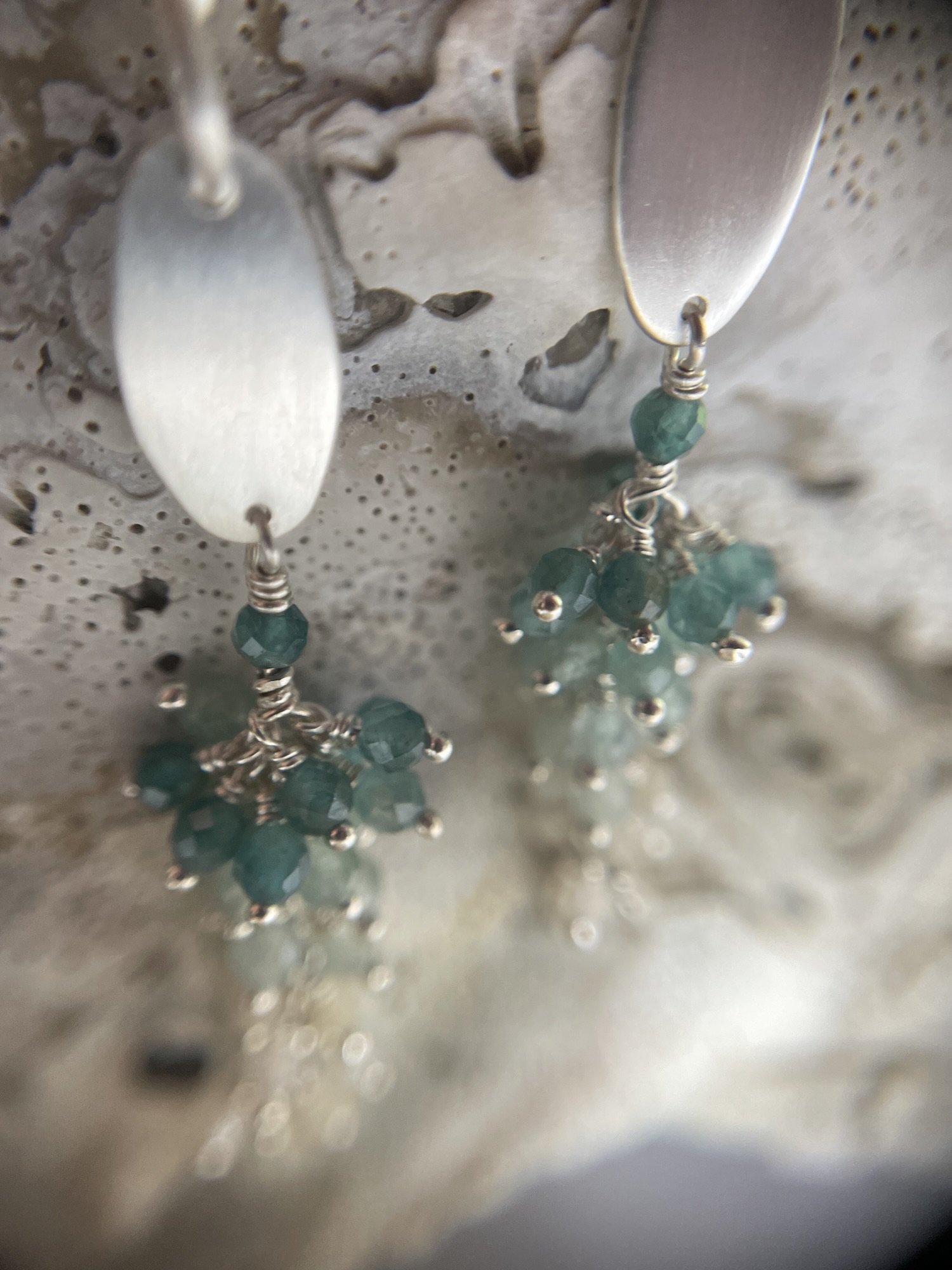 Detail view of Sterling silver teal blue grandiderite and off white opal gemstone dangle earrings.