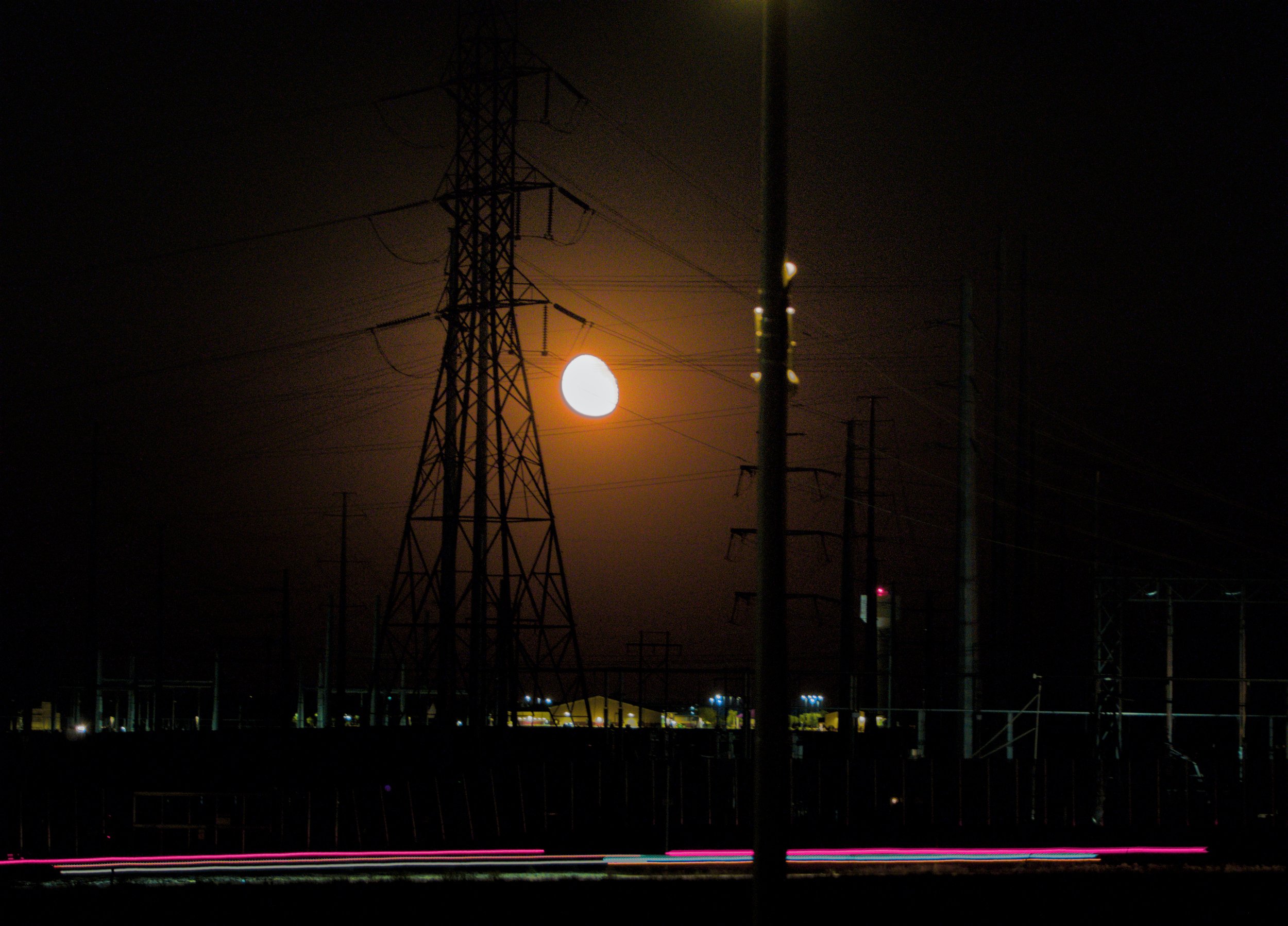 moon through power lines above city