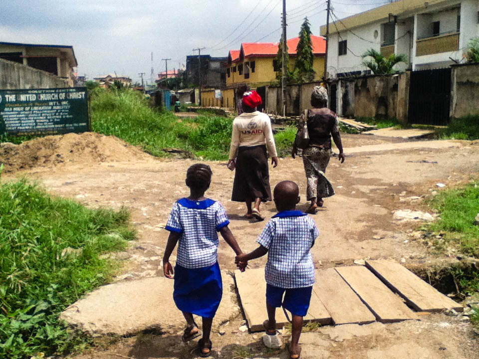   In Ago Okota, Gift (7) and Elijah (5) walk hand in hand towards their home.  