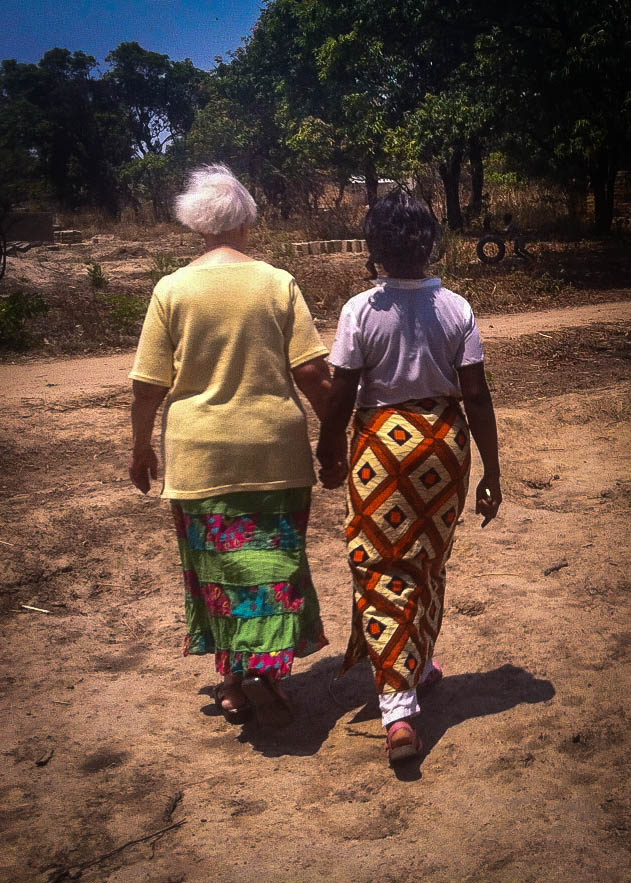 Oumie walking hand in hand with a Care Worker in one of our most vulnerable communities