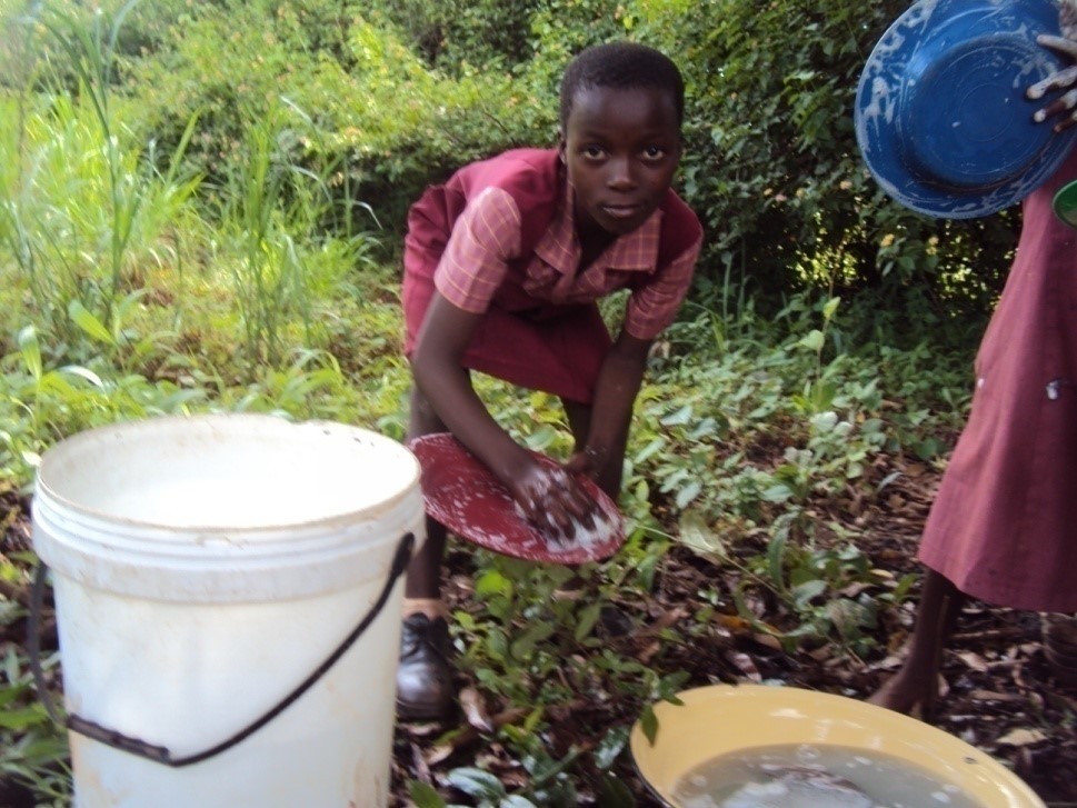 Nomsa helps her Care Workers clean dishes after her daily meal at the local Care Point in Honde Valley
