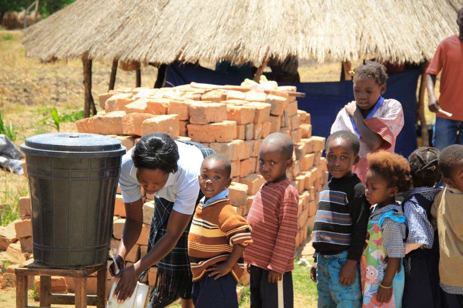  The children wait patiently as one of the Care Workers fills up a bucket of water. 