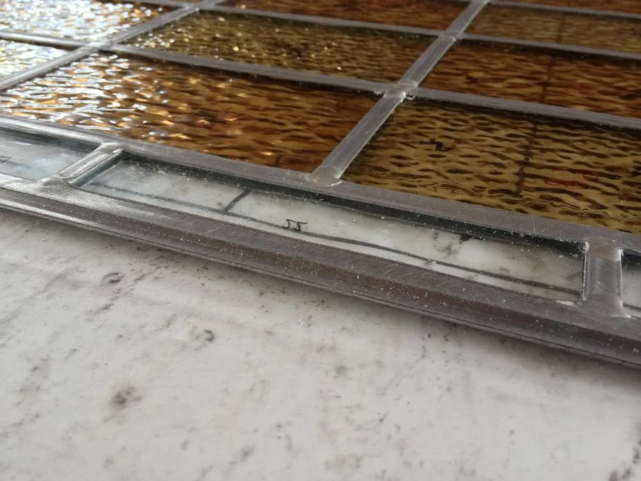 Y-shaped lead around a panel for encapsulation. Spacers around the edge of the double glazed unit grip the "flange".