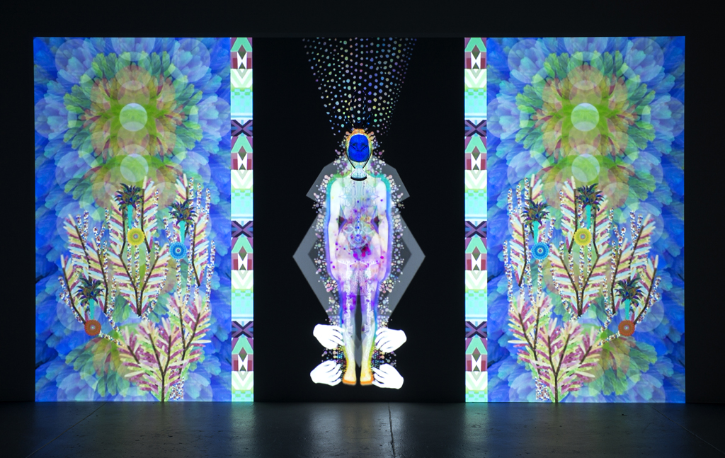 Saya Woolfalk, ChimaCloud: Gate , 2017, Single channel HD Video projection (continuous loop); acrylic gouache on wood, Projection: 95-1/2 x 171 inches, Sculpture: 26-1/2 x 9 x 4-1/2 inches. Copyright Saya Woolfalk, courtesy Leslie Tonkonow Artworks + Projects, New York