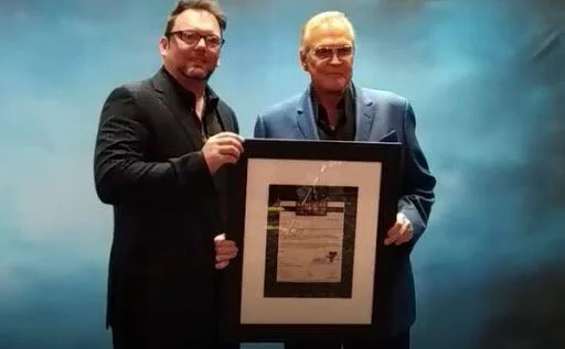 Lee Majors accepting his confirmation for induction letter from HOF Executive Director Anthony Hudson.