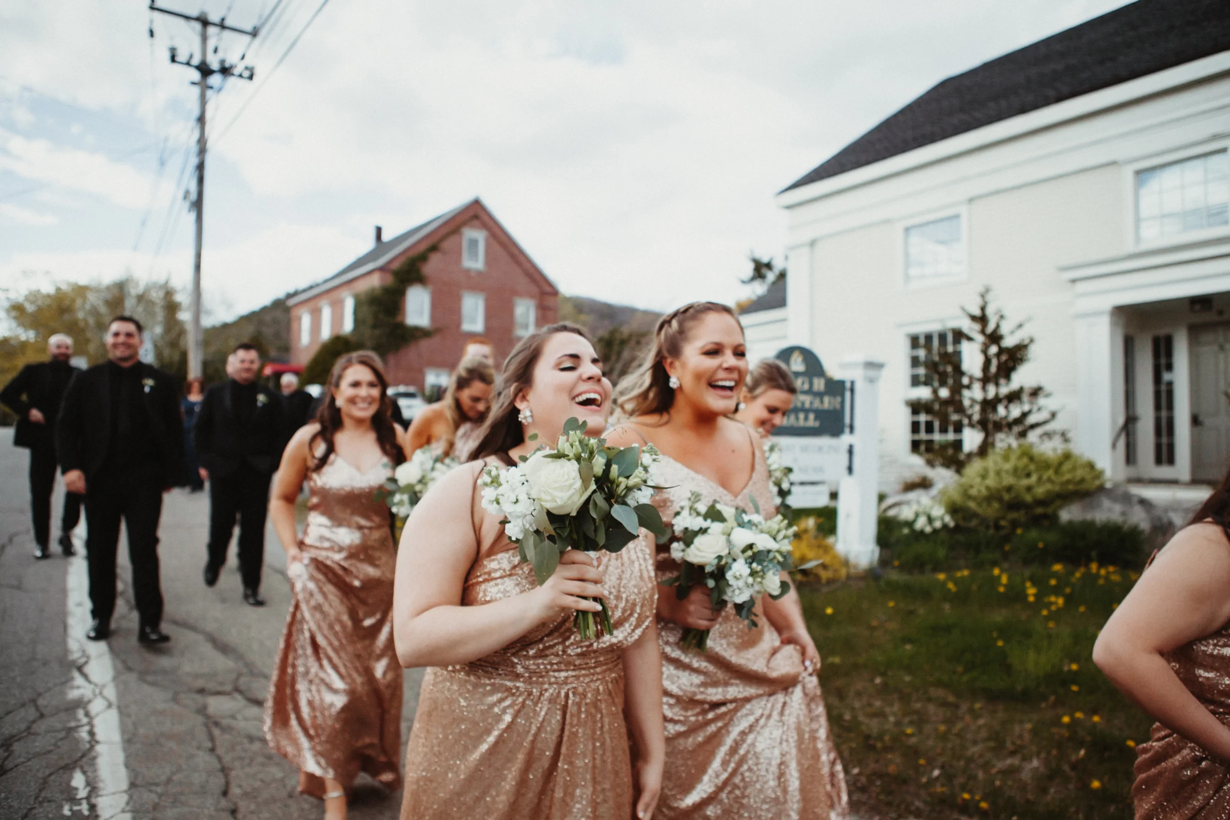 Glam bridesmaids laughing while leaving the ceremony