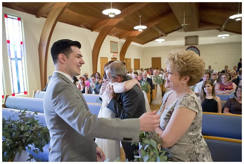 The groom being welcomed by his new Mother in Law and Dad hugging his little girl in the background.