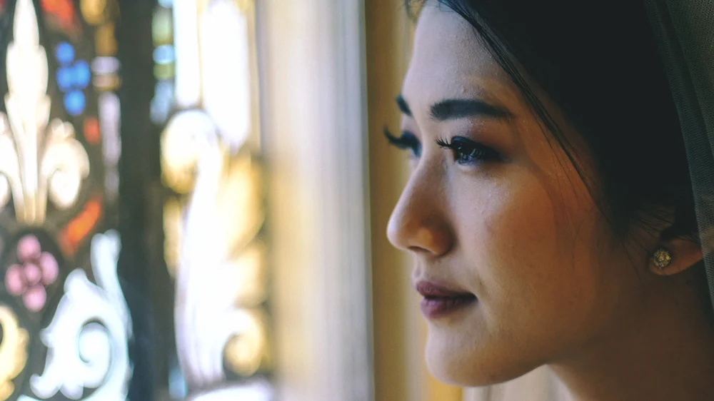 Bridal portrait beside a stained-glass window.