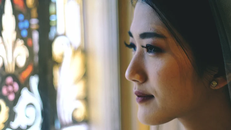 Bridal portrait beside a stained-glass window.