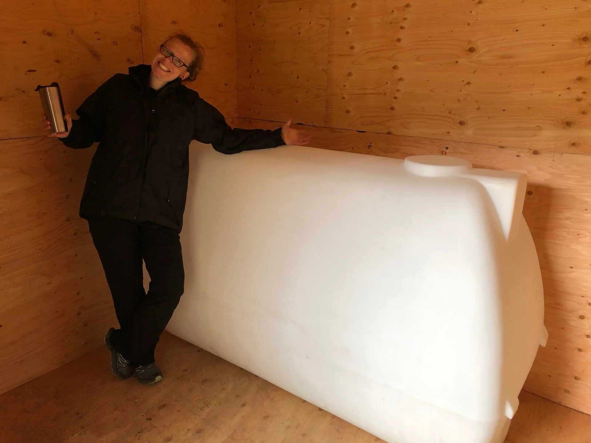 The inside, with Justine posing with our 450 gallon holding tank. The water guy suggested this size, to give the water the ability to settle,a nd to provide some back up for our somewhat slow well. Our neighbour went with 4,000 gallons…