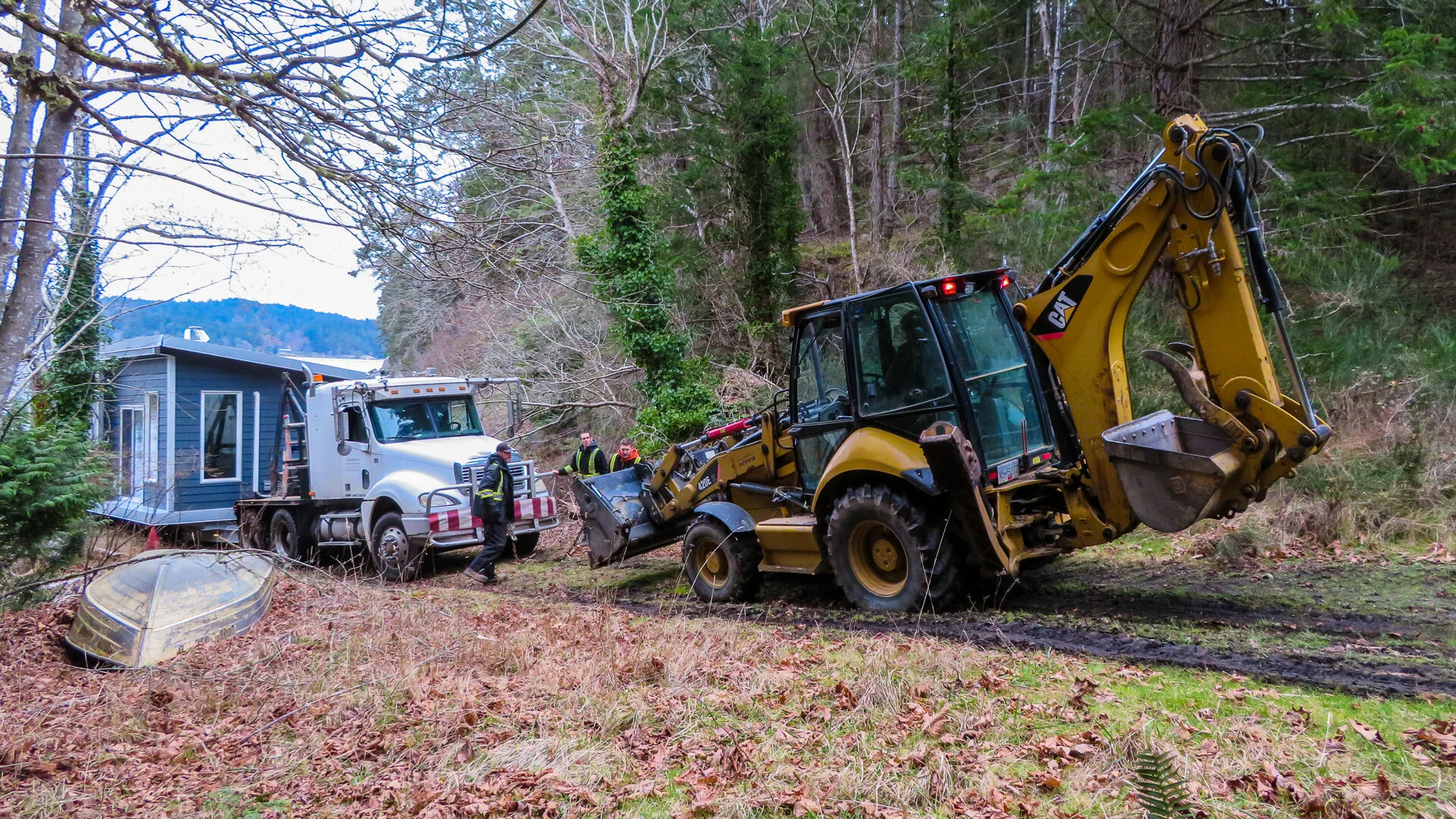  And it didn’t take long for the truck to get stuck. Once it was fully off the barge, it got stuck on the slick, muddy hill. It was a good thing we had the backhoe, or we were stuck. They chained it up and started pulling.  