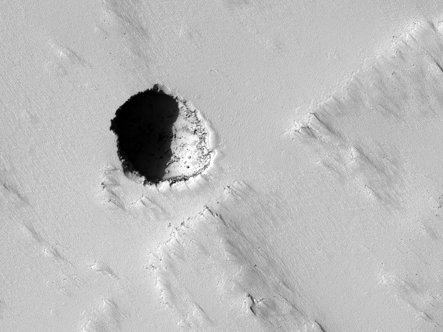 Seventh grade students asked Nasa to take this high-res picture of Mars using the Mars Reconnaissance Orbiter's HiRise camera. It may be a skylight cave - the collapsed roof of a lava tube - and could be a target for future human explorers. Credit: Nasa/JPL/University of Arizona