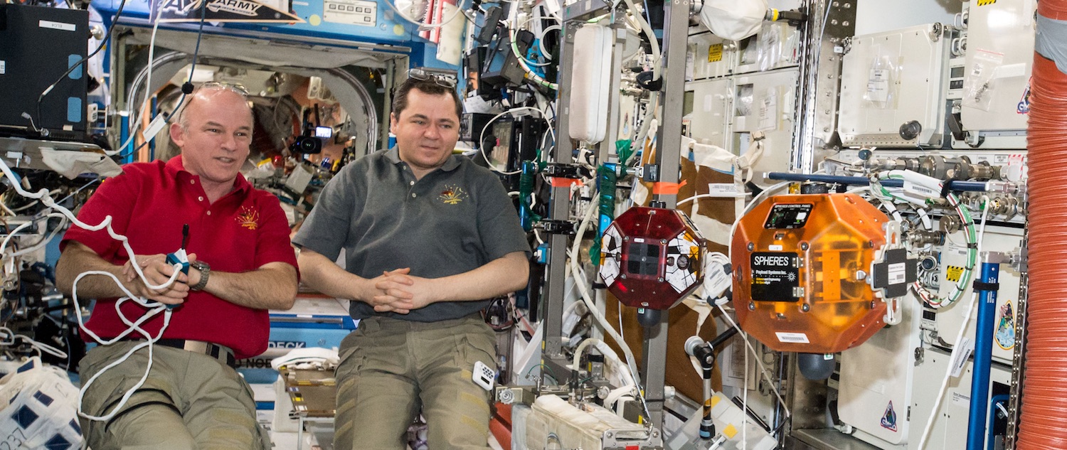 US astronaut Jeff Williams and Russian cosmonaut Oleg Skripochka monitoring the SPHERES satellites (the red and orange objects to the right) during the 2016 Middle School Zero Robotics Tournament last summer. Credits: Nasa Ames