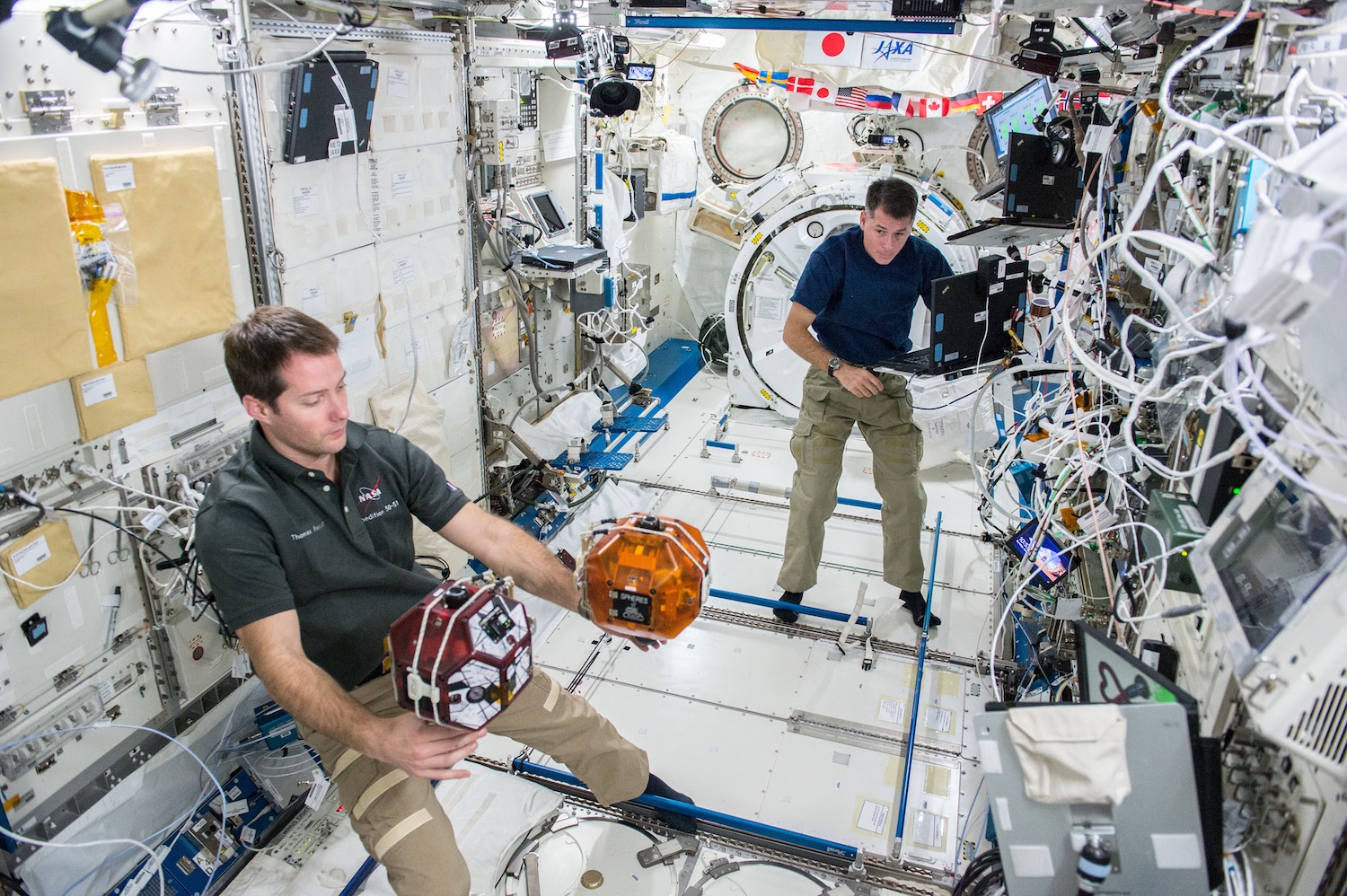 The Spheres robots are working tools on the International Space Station. This picture shows a recent test of space tether technology. Every summer middle school students across the United States get a shot at controlling the robots in the Zero Robotics competition. Credit: Nasa