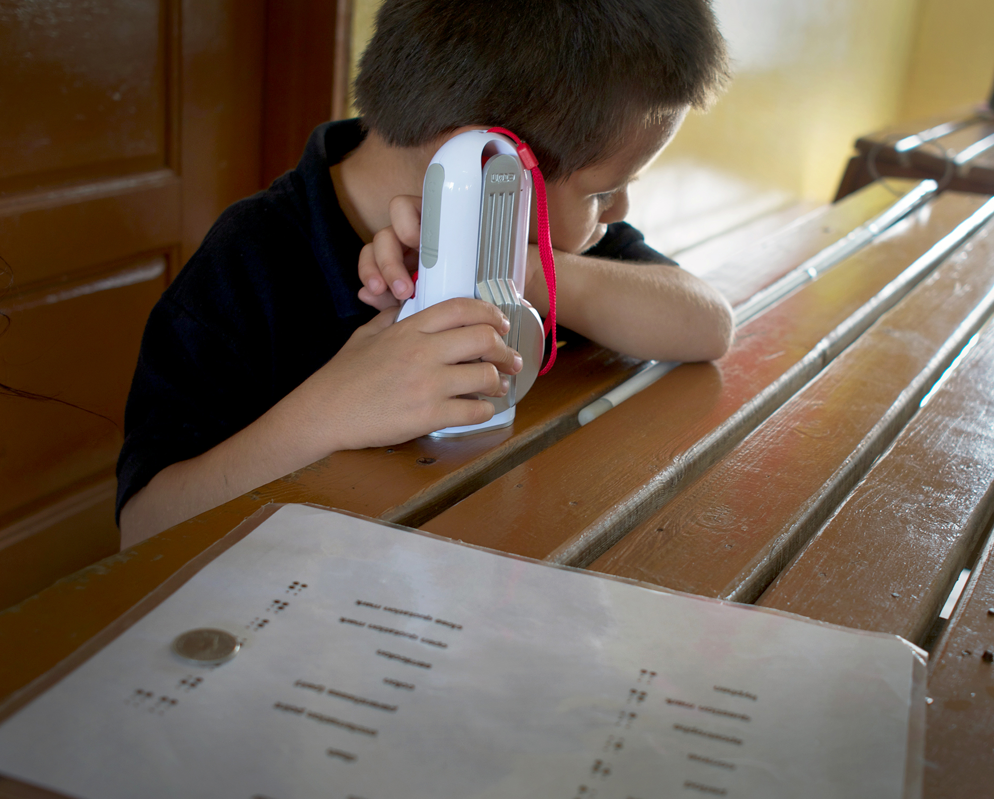 A student listens to the Belize national soccer team play a friendly match against New England on his new self-powered radio.