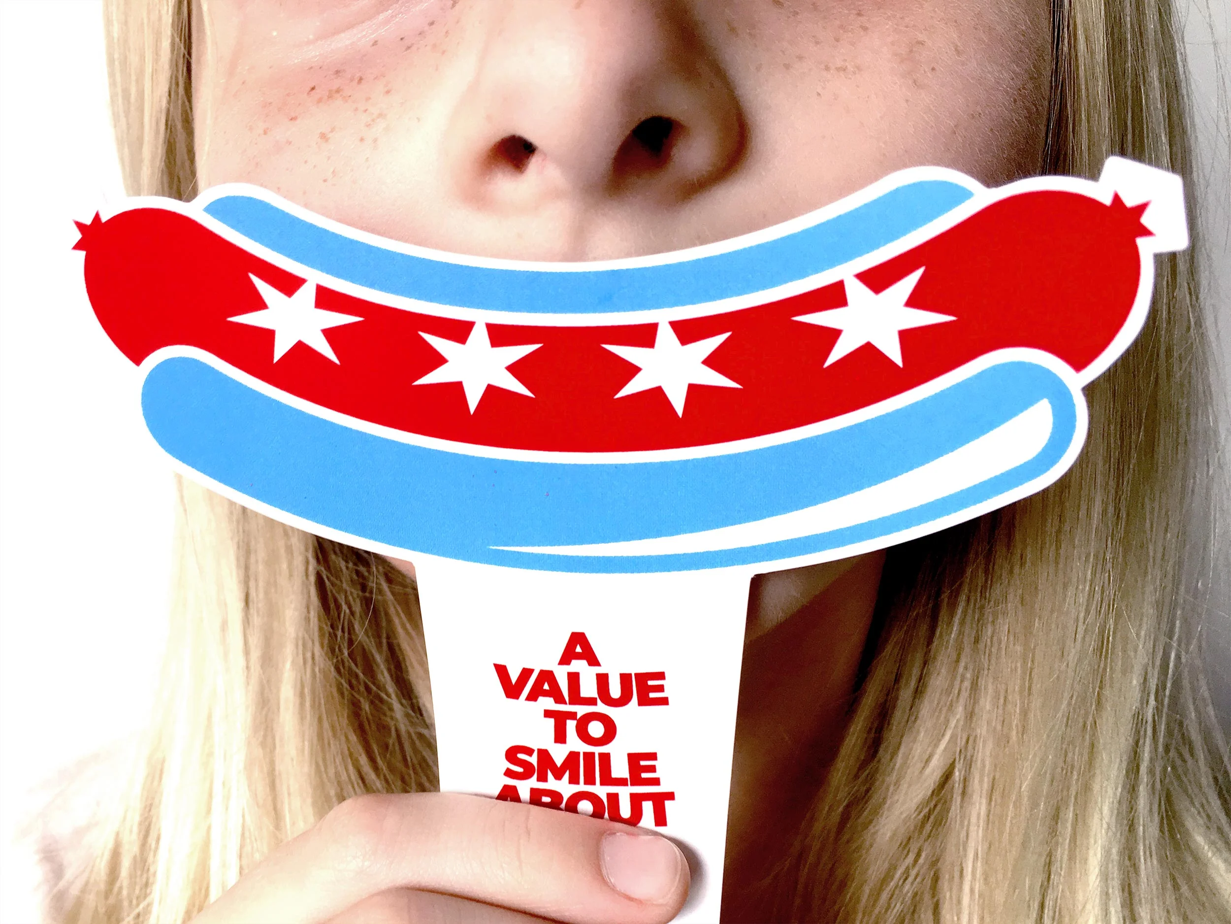 Smile inducing game day coupon featuring the main shape of the Chicago Dogs logo with a handle to hold in front of a child's face to make a Chicago Dogs fan smile