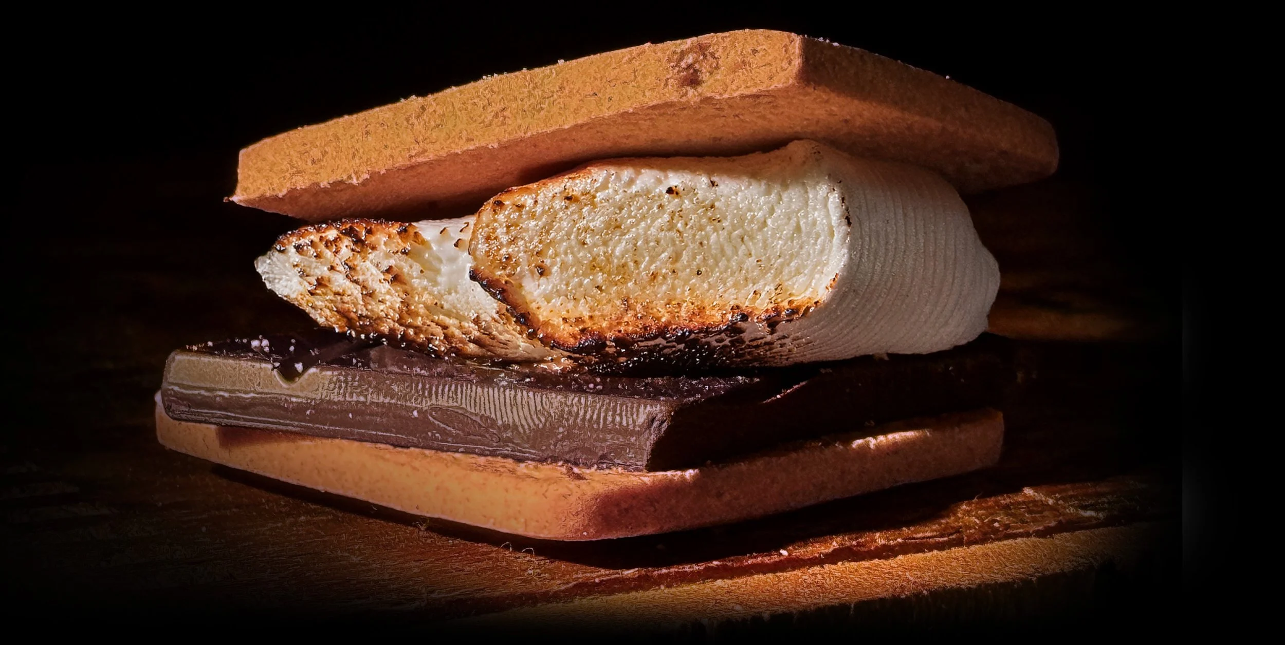 Close-up of a mouthwatering layered s'more lit by flashlight