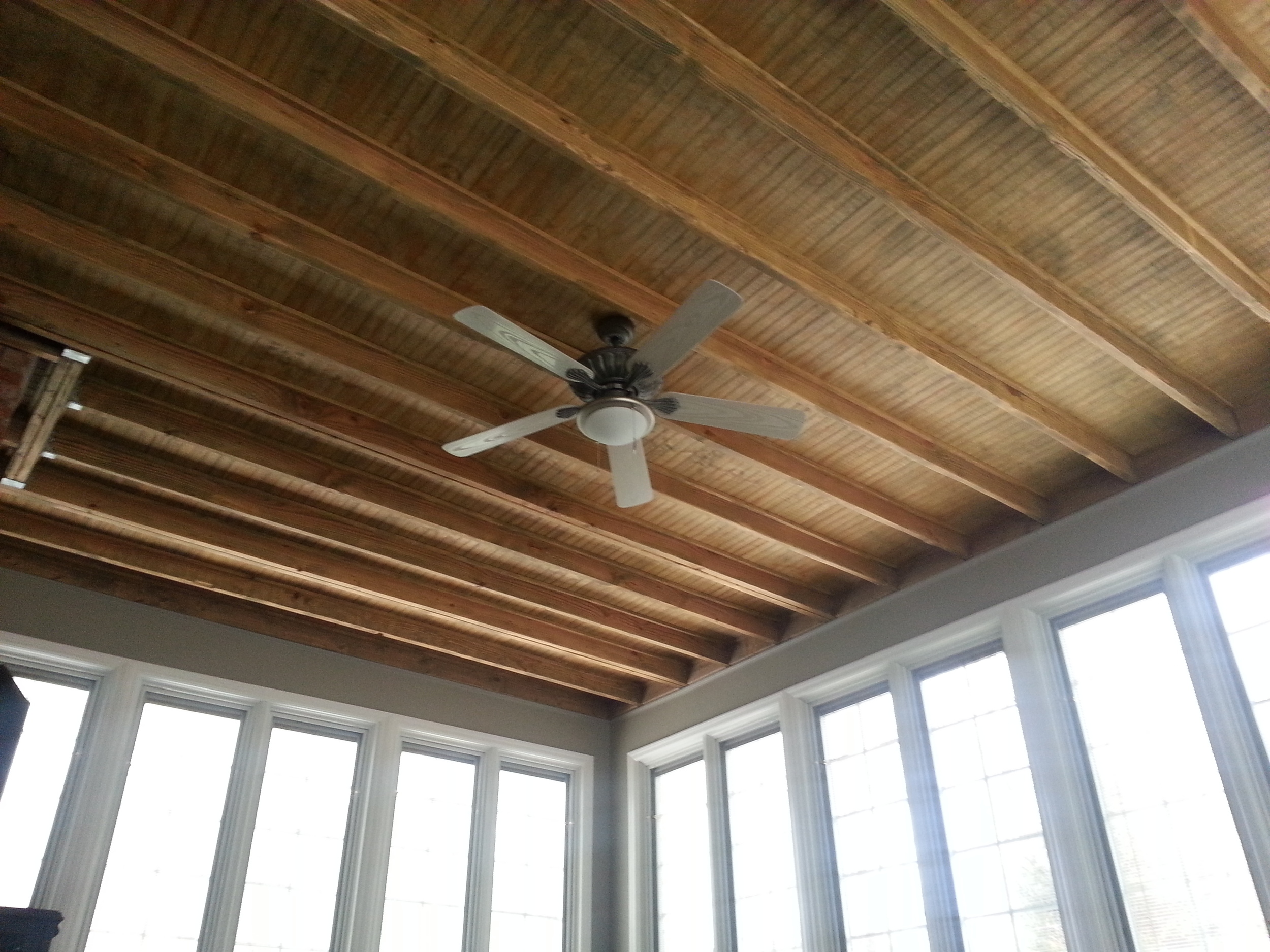 Custom sun room with stained exposed rafters. Installation by Groundswell Contracting