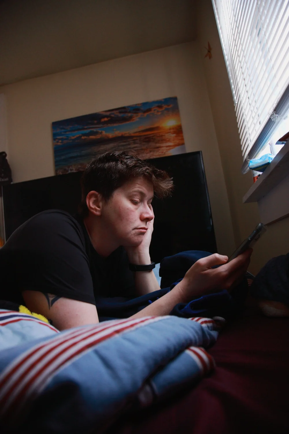 young person scrolling mobile phone on bed