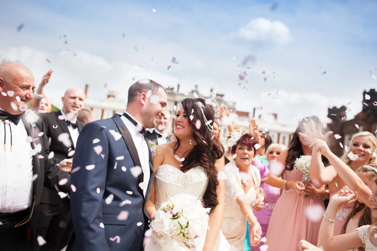 A bride and groom sharing a loving look as friends and family throw conetti at Knowsley Hall in Liverpool