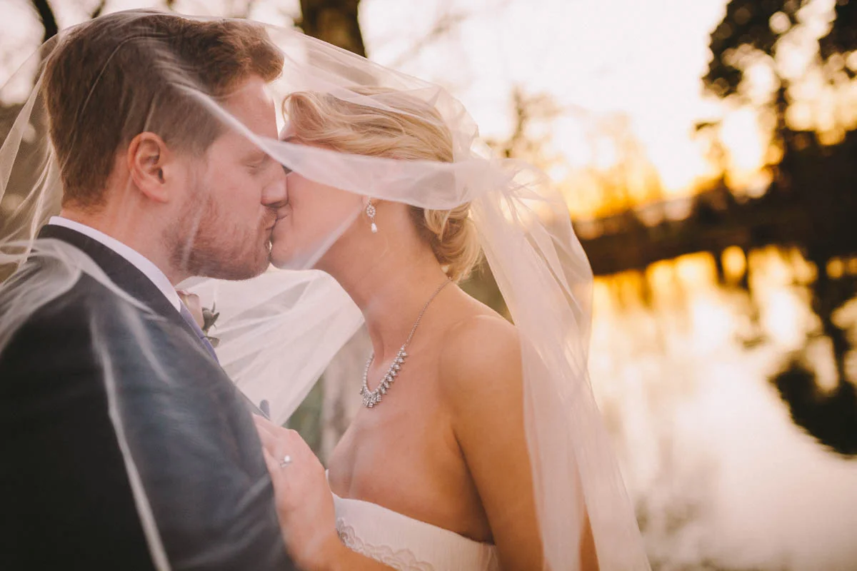 A Bride and Groom kiss beneath her veil at Sunset.jpg