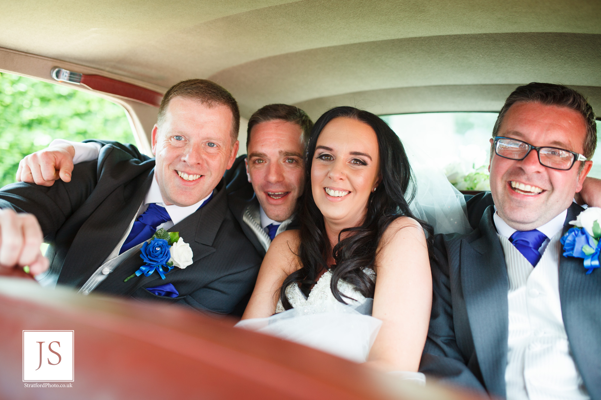 A bride and groom sqeeze into the back of their Bentley wedding car with two of their groomsmen.jpg