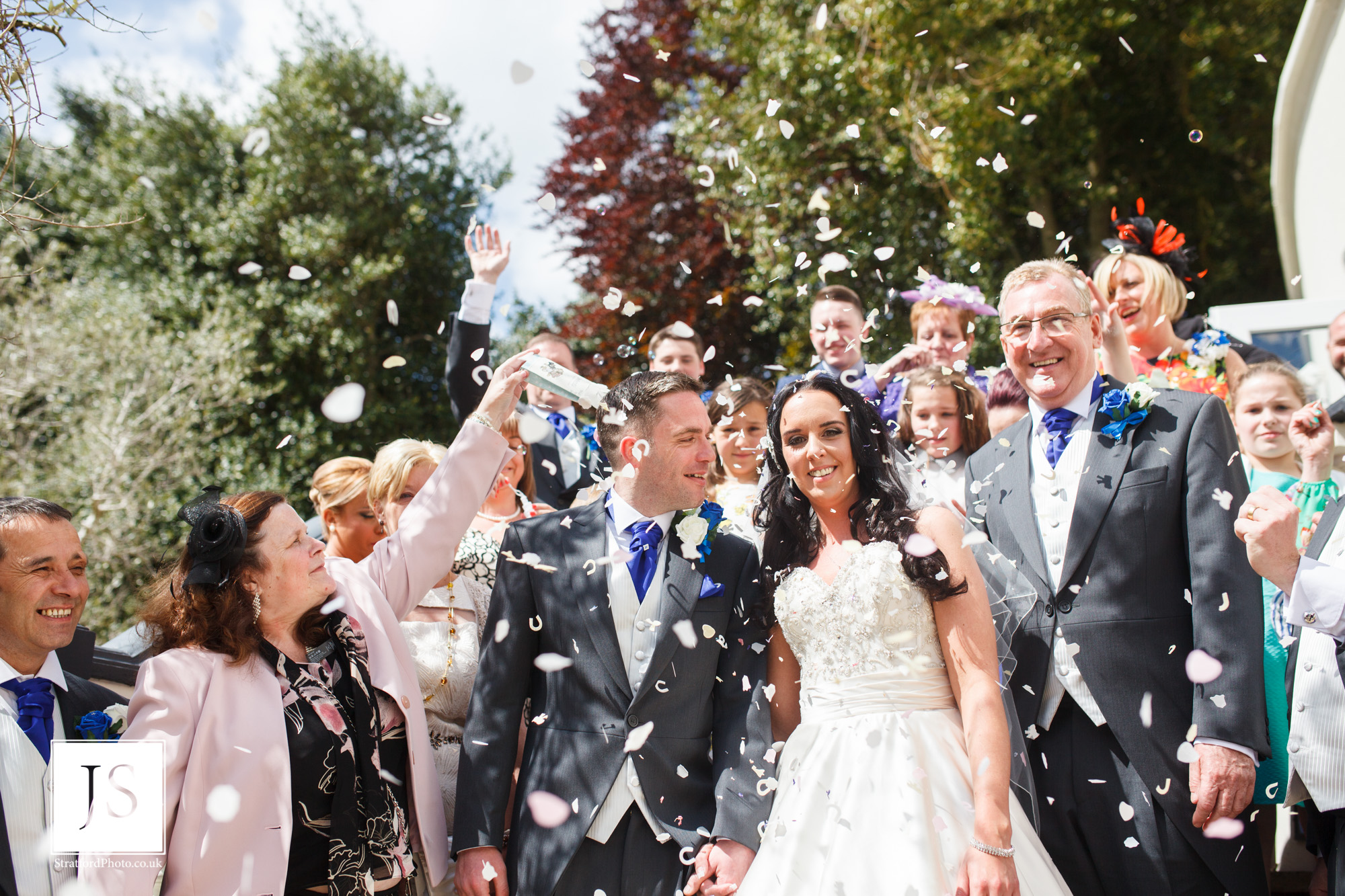 A bride and groom smile under confetti on a hot wedding day.jpg