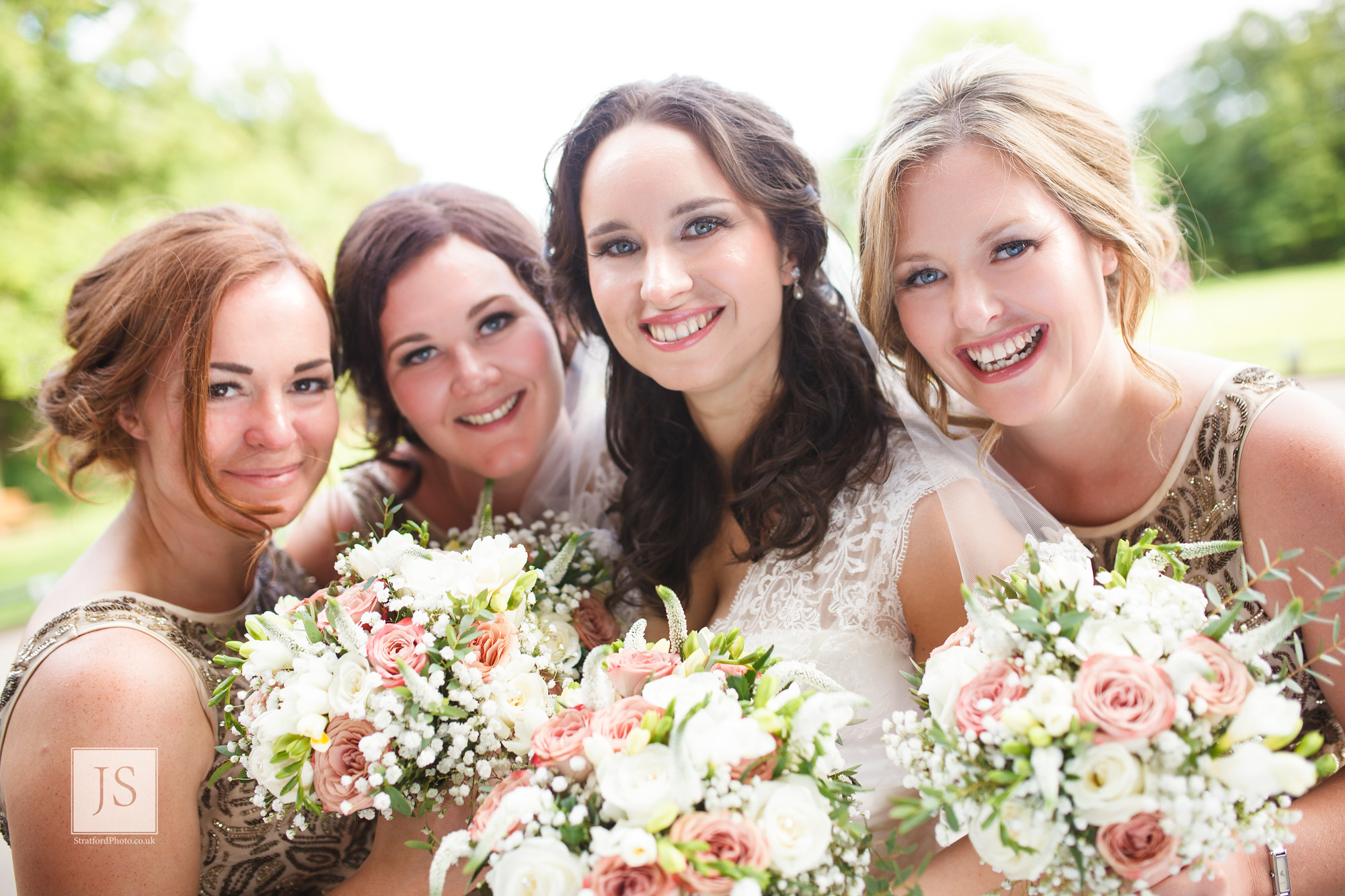 A bride with her bridesmaids smile with their posies.jpg