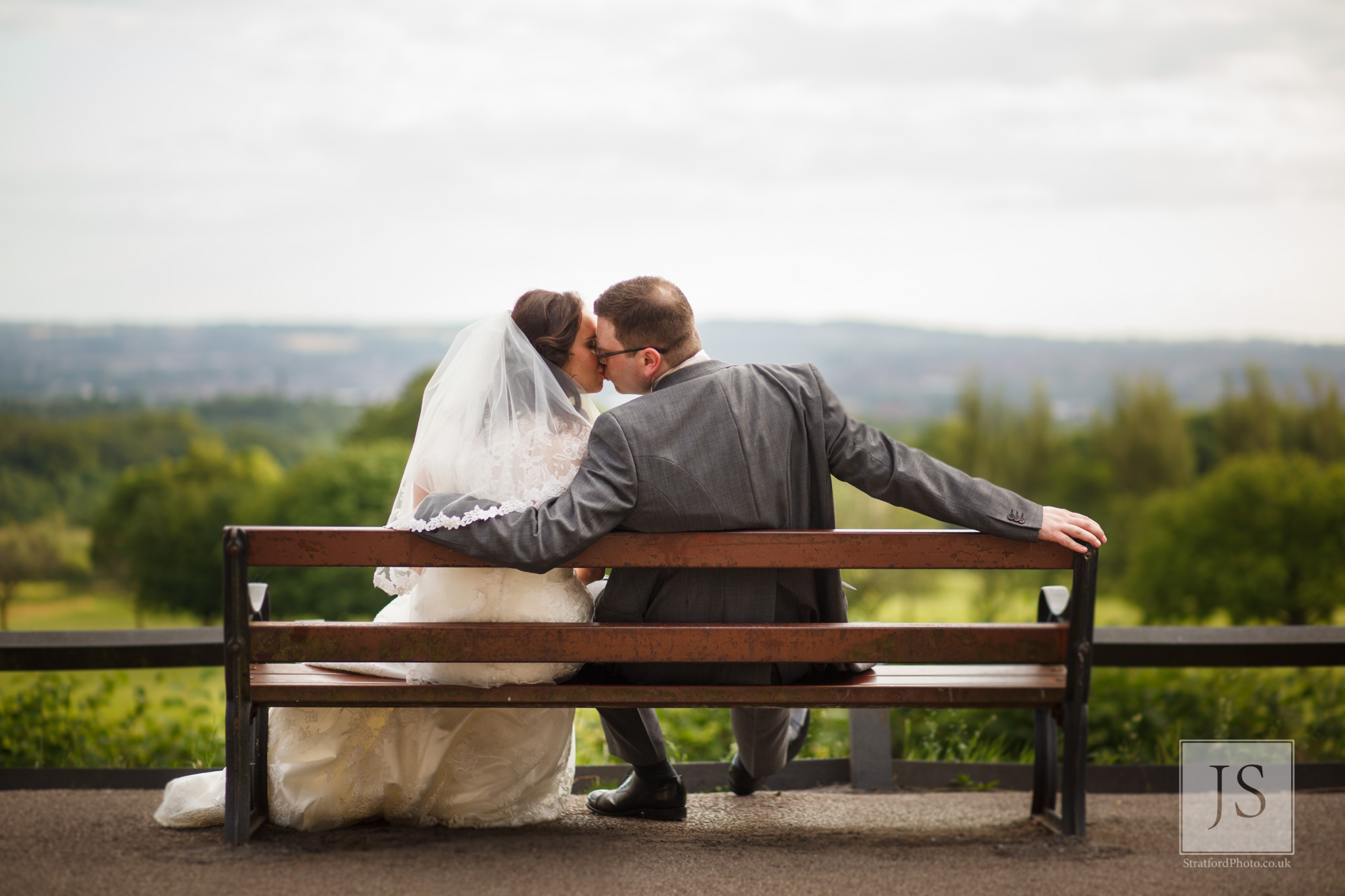 A couple kiss on a bench with the Lancashire hills in the background at Haigh Hall.jpg