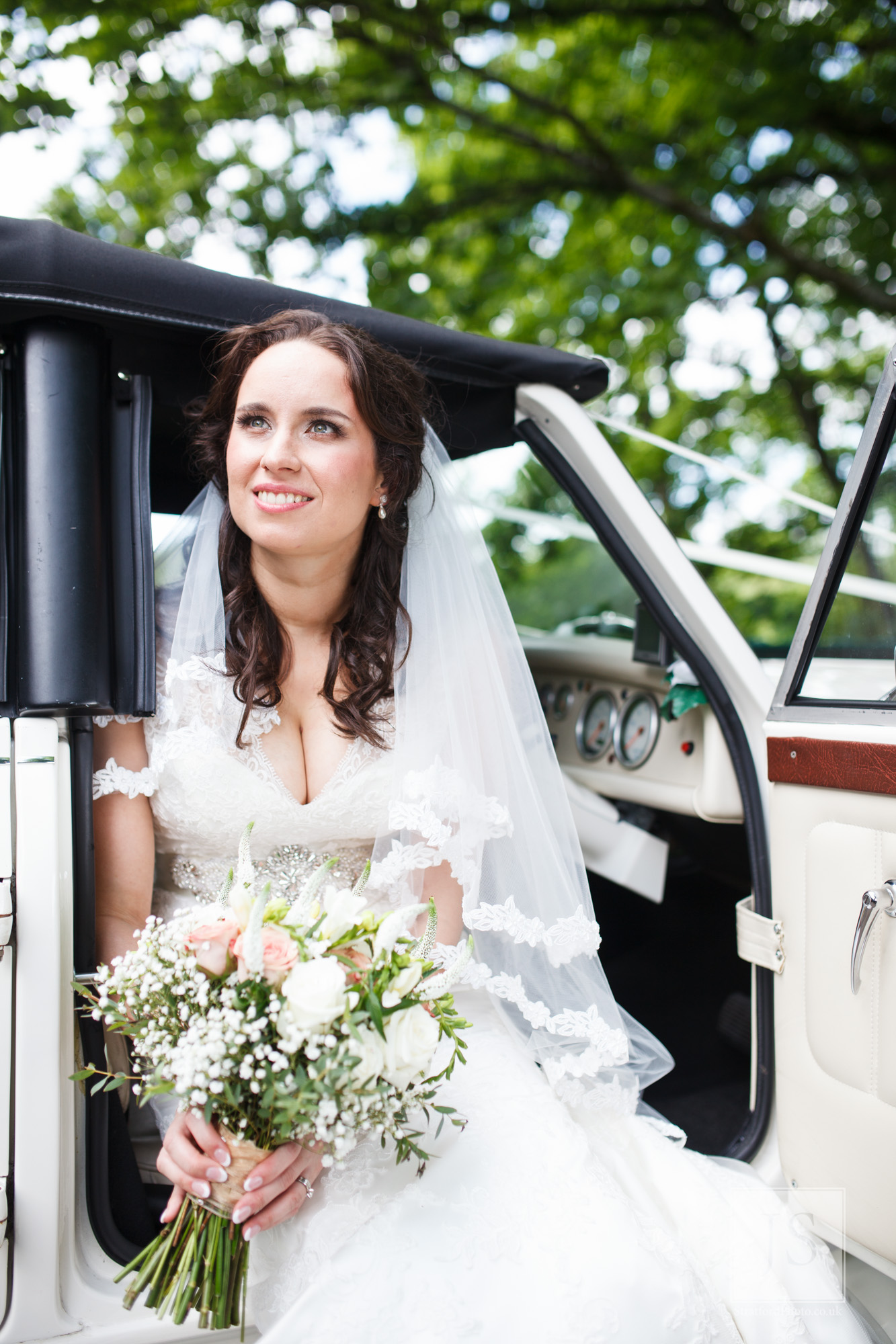A bride perrches on the seat of her Bentley wedding car.jpg