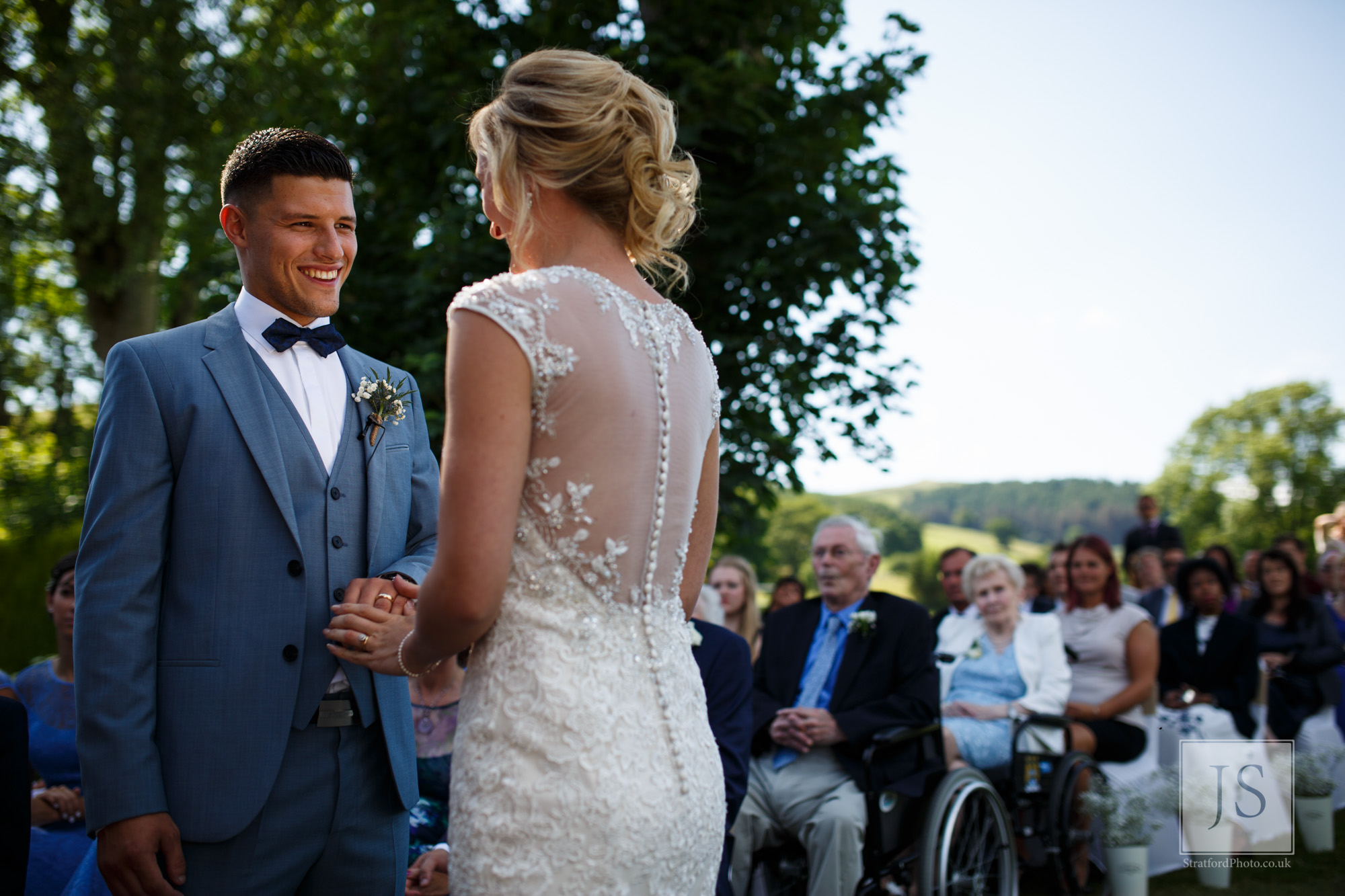 A groom smiles at his beautiful bride with the Welsh mountains behind.jpg