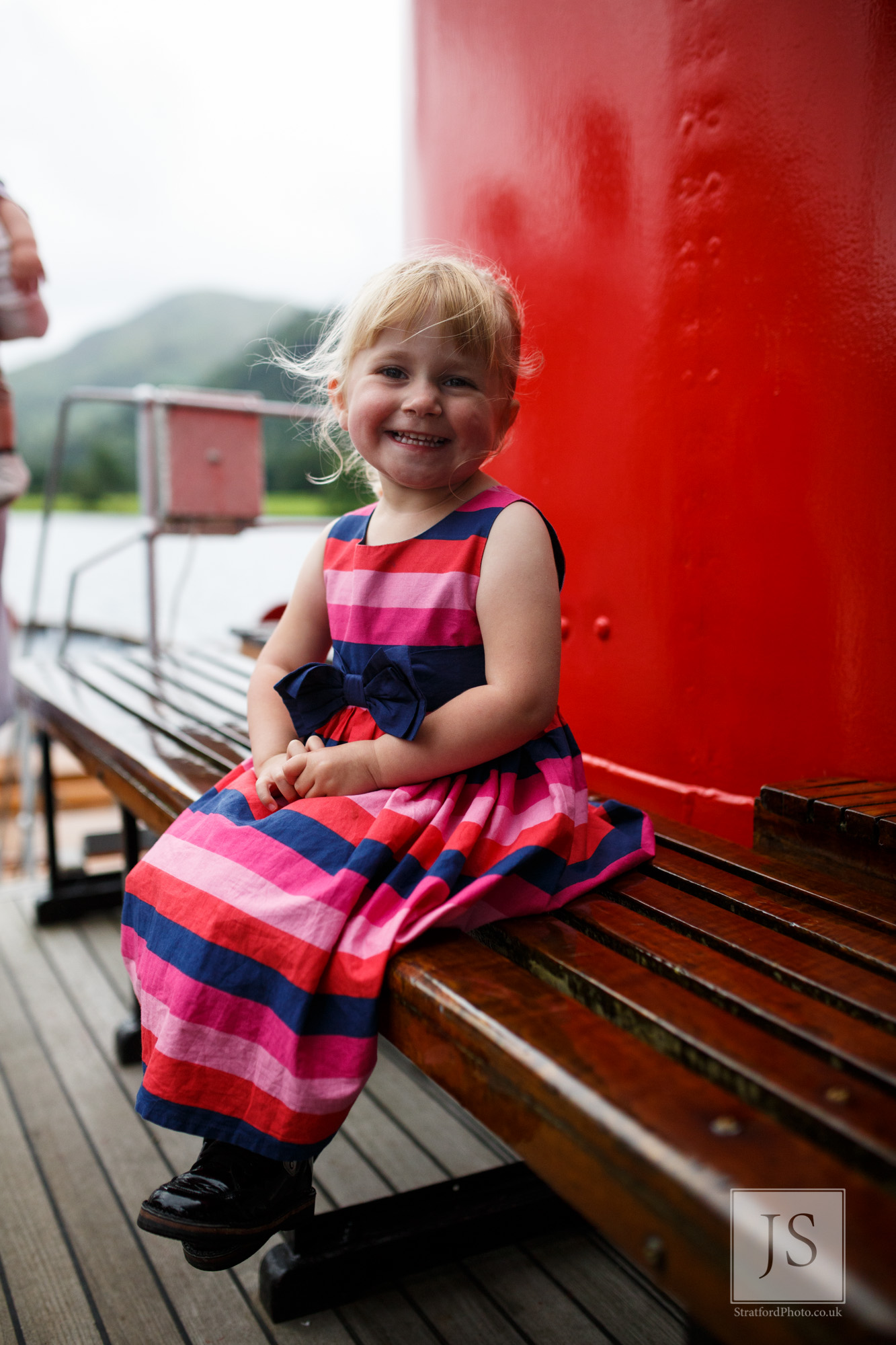 A beautiful little girl smiles at the camera on a Lake Ullswater boat.jpg