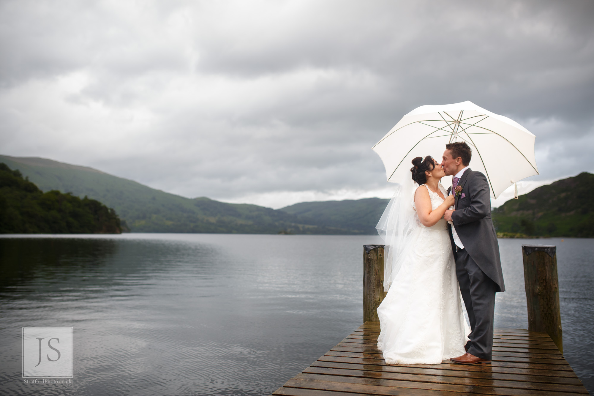 A bride and groom kiss on a jetty at Lake Ullswater.jpg