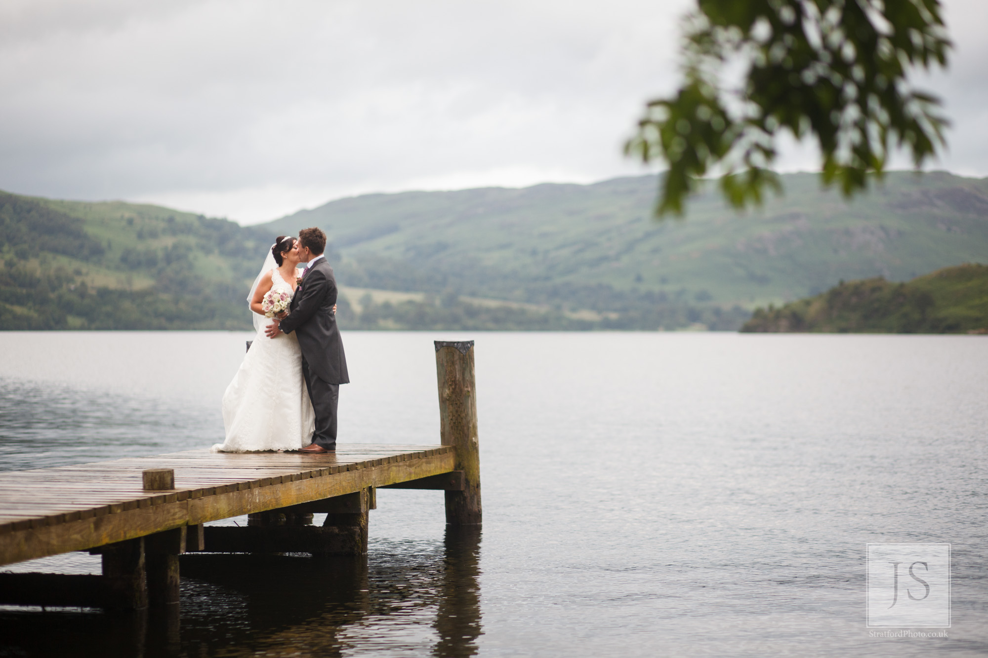 A bride and group kiss at the end of a jetty on Lake Ullswater.jpg