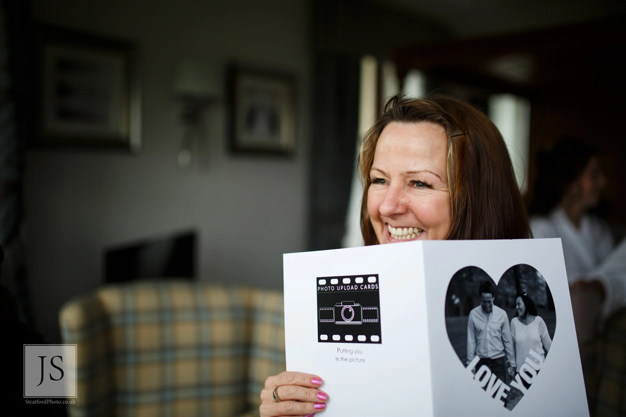 A wedding guests hides behind a wedding card smiling.jpg