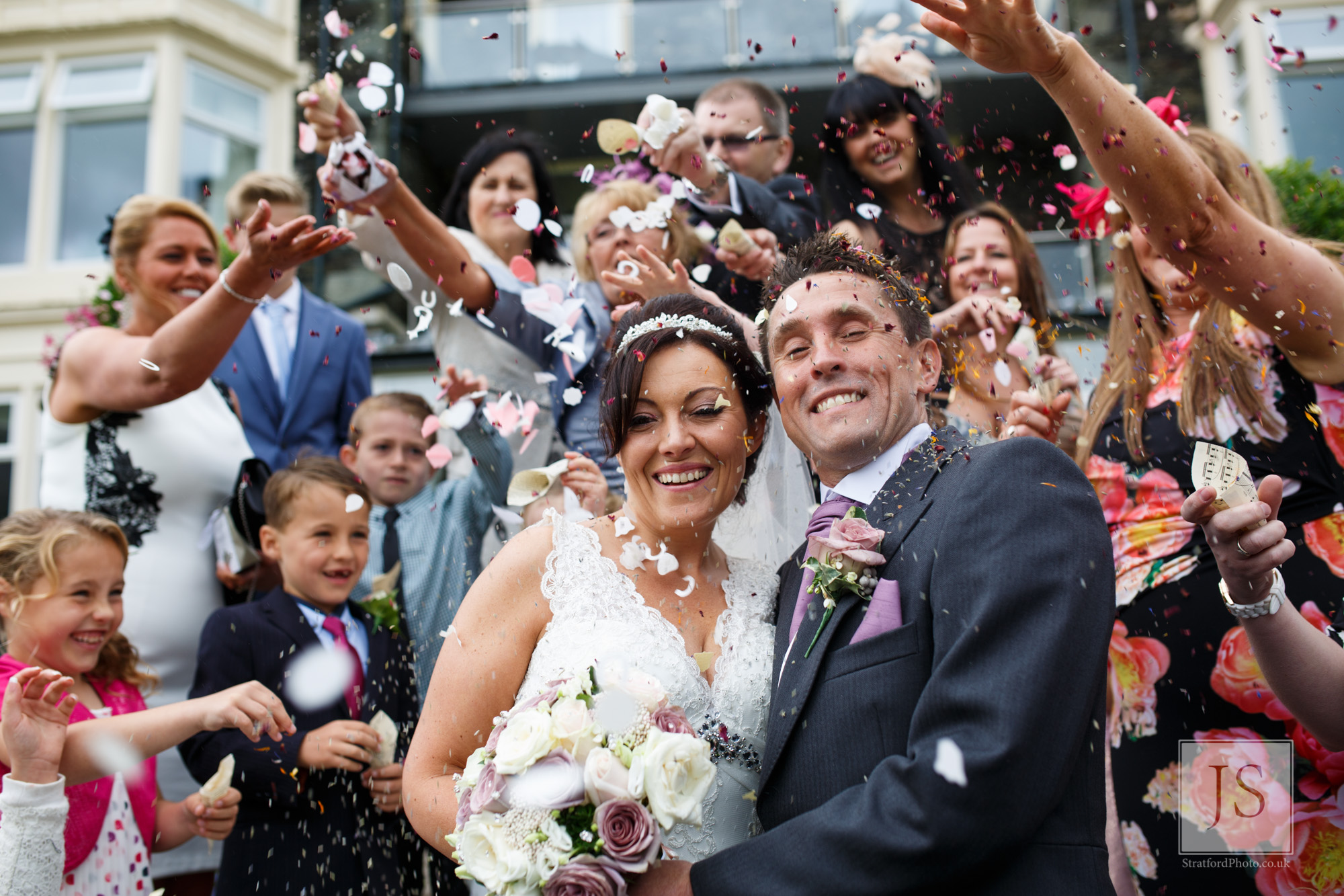 A bride and groom smile as confetti is thrown over them.jpg